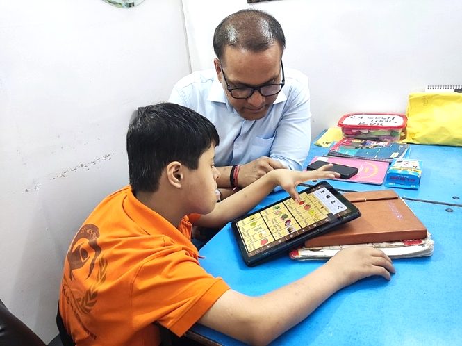 A therapist and a child using an AAC communication app on a tablet