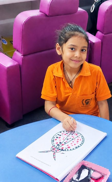 A girl in the A3C uniform colouring at a table