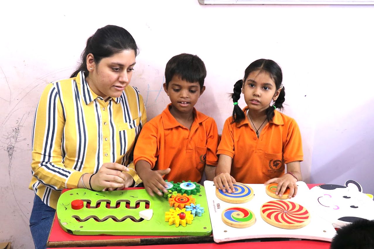 A special educator with two A3C children using fine-motor and sensory boards