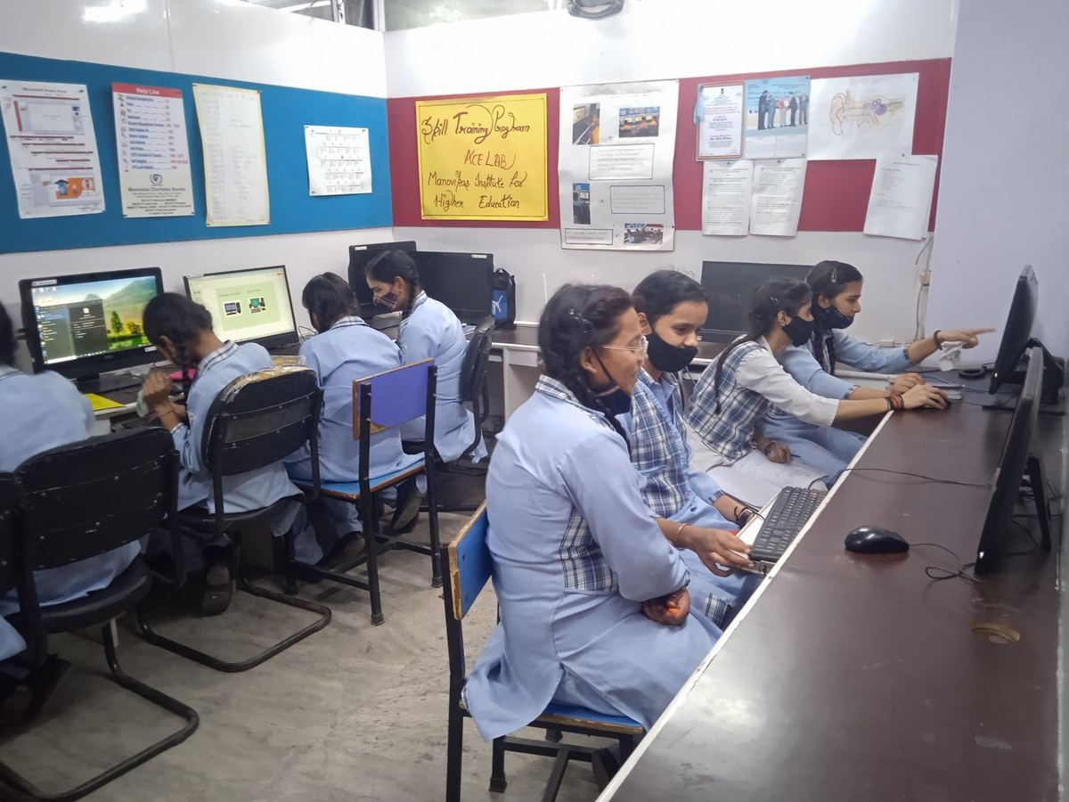 Learners at desktop computers in the ACE Lab, with the ACE Lab sign on the wall behind them