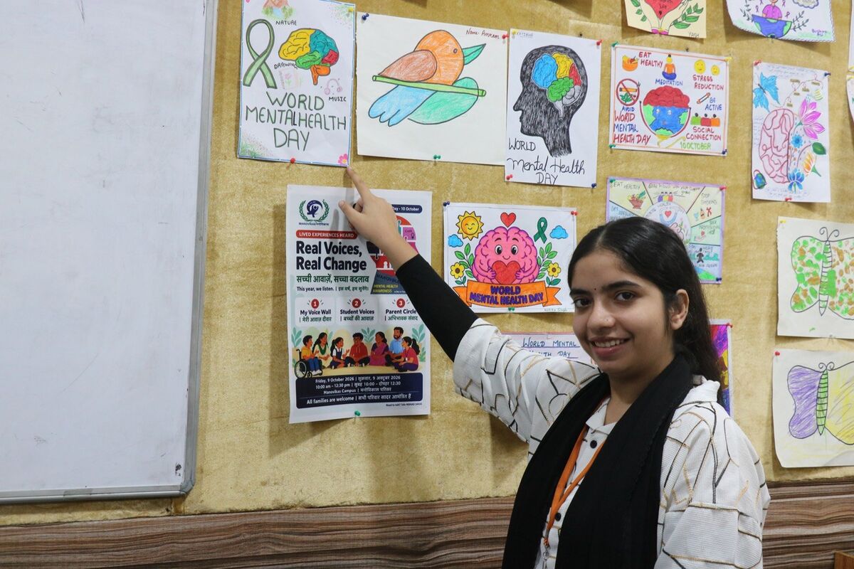 A D.Ed. trainee points to the Real Voices, Real Change poster in the mental health poster gallery