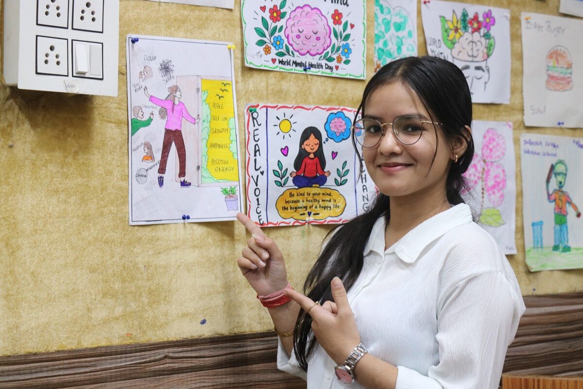 A D.Ed. trainee beside hand-drawn mental health awareness posters